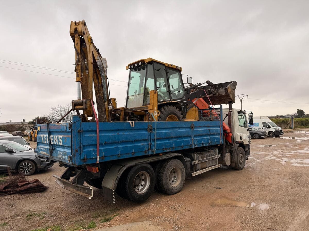 Camión TERENS azul con grúa, estacionado al aire libre contra un cielo nublado.