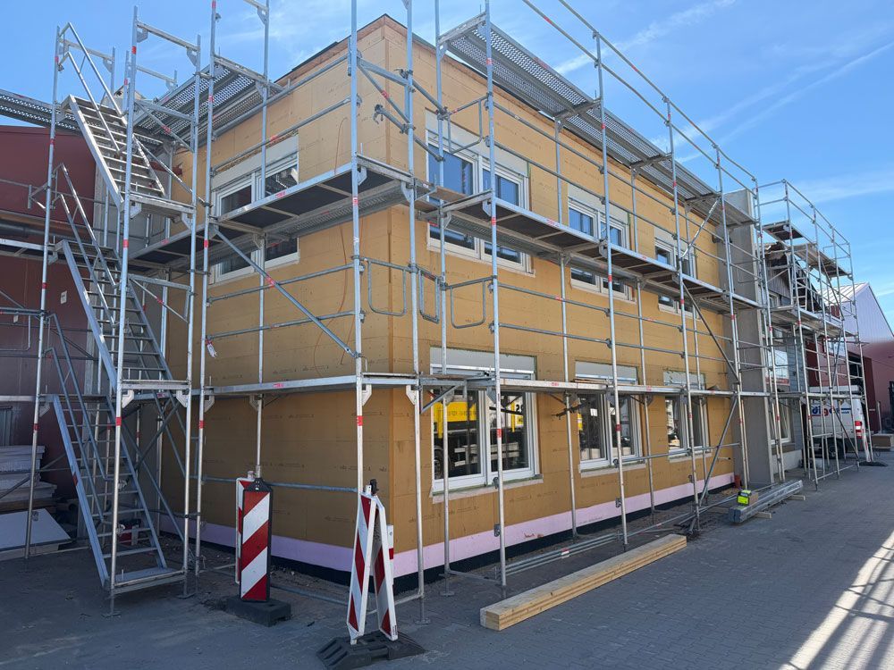 Ein Gerüst umgibt ein gelbes, im Umbau befindliches Gebäude an einer Straßenecke.