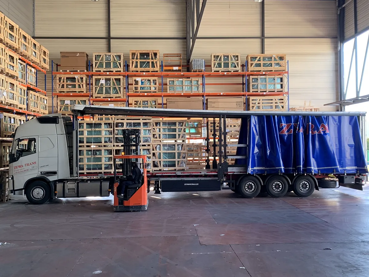 Una carretilla elevadora está cargando un camión semirremolque en un almacén.