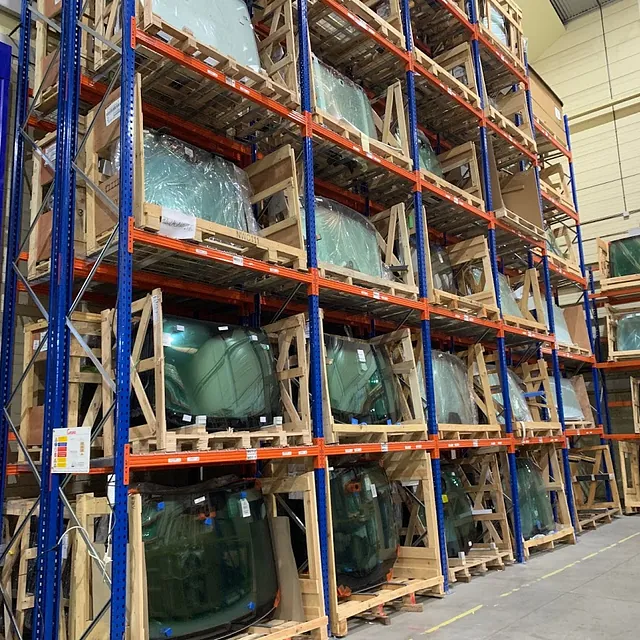 Un almacén lleno de muchos parabrisas sobre paletas.