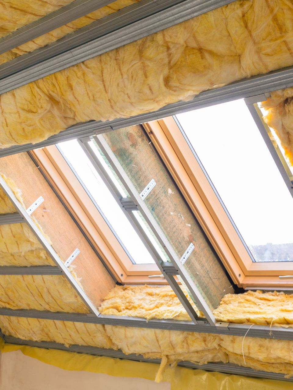 Installation d'un puits de lumière avec isolation apparente et ossature métallique au plafond.