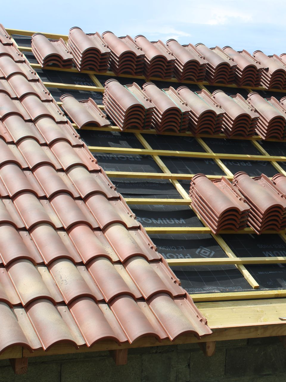 Pose d'une toiture en tuiles de terre cuite rouge.