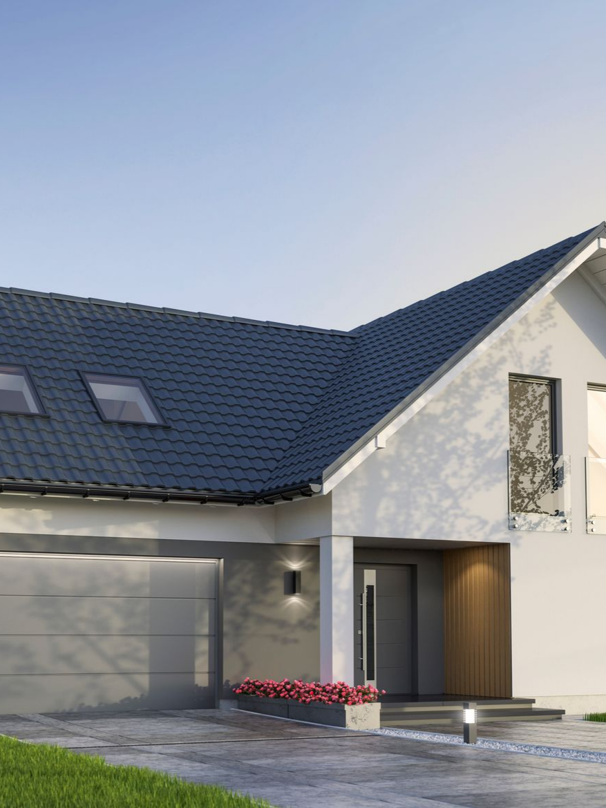 Maison blanche moderne avec toit gris et garage. Fleurs rouges près de l'entrée.