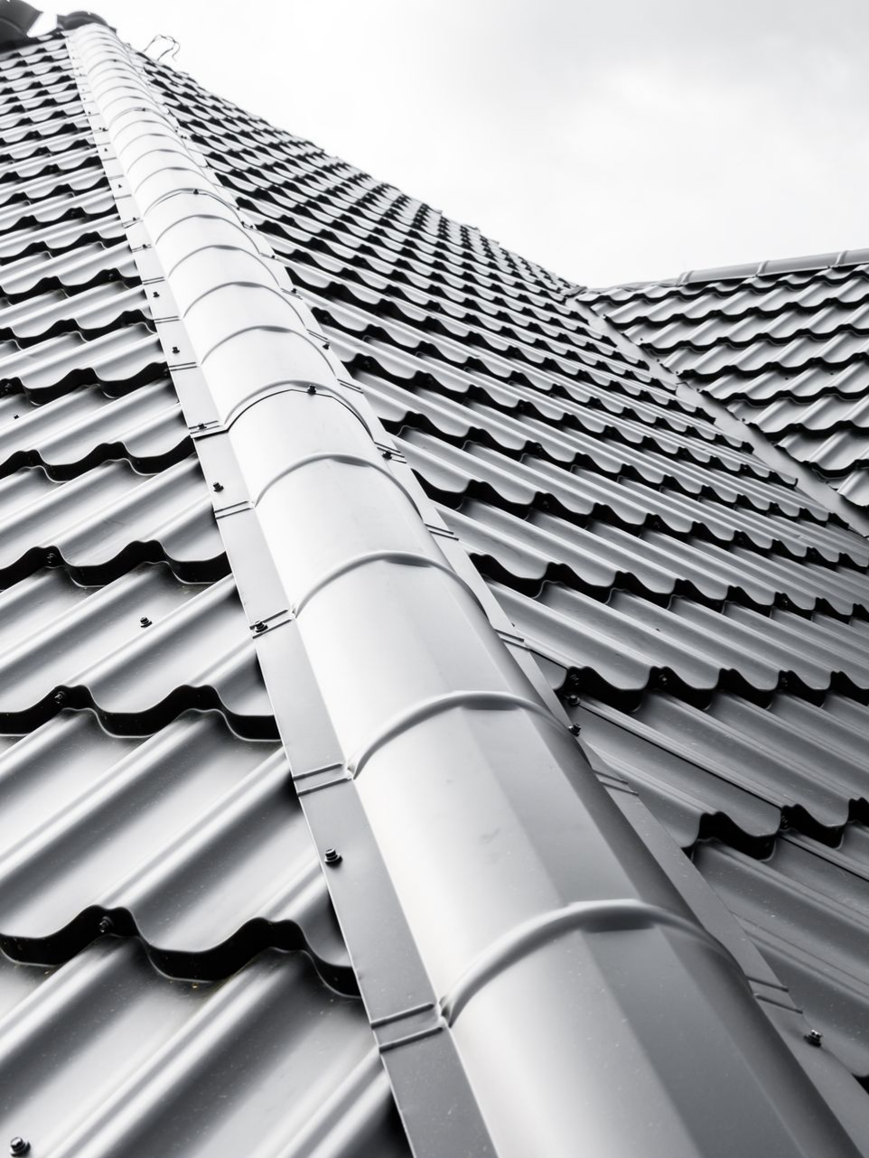 Toiture métallique grise avec un grand conduit de ventilation cylindrique vertical.