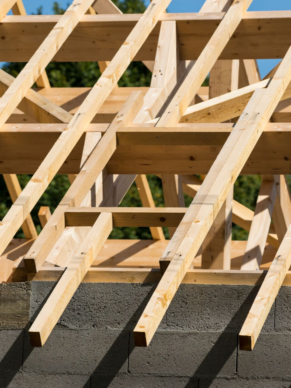Charpente de toit en bois en construction sur un mur de parpaings gris.