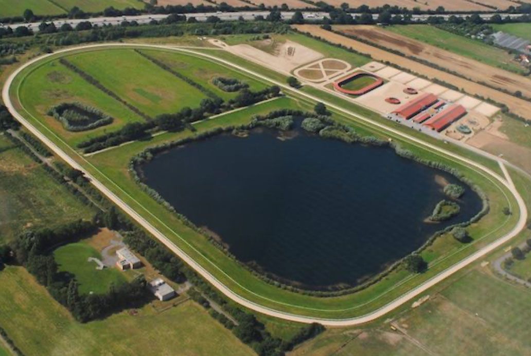 Luftaufnahme einer Rennstrecke mit einem großen See in der Mitte und Trainingsanlagen.
