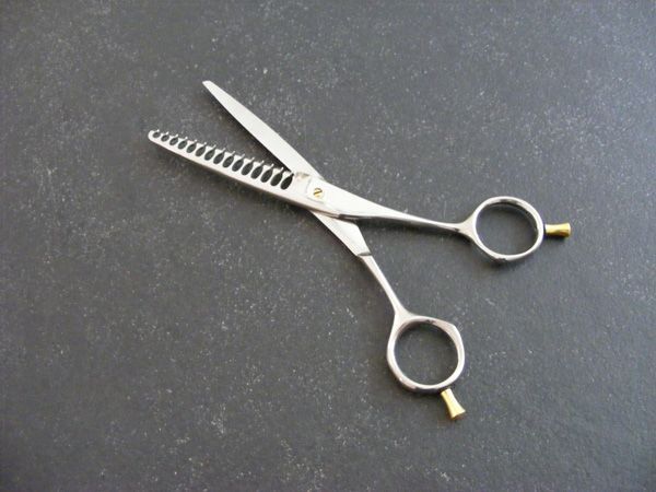 Eine Schere liegt auf einer schwarzen Oberfläche