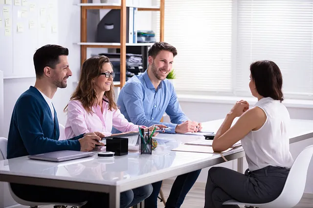 Un grupo de personas están sentadas alrededor de una mesa teniendo una reunión.