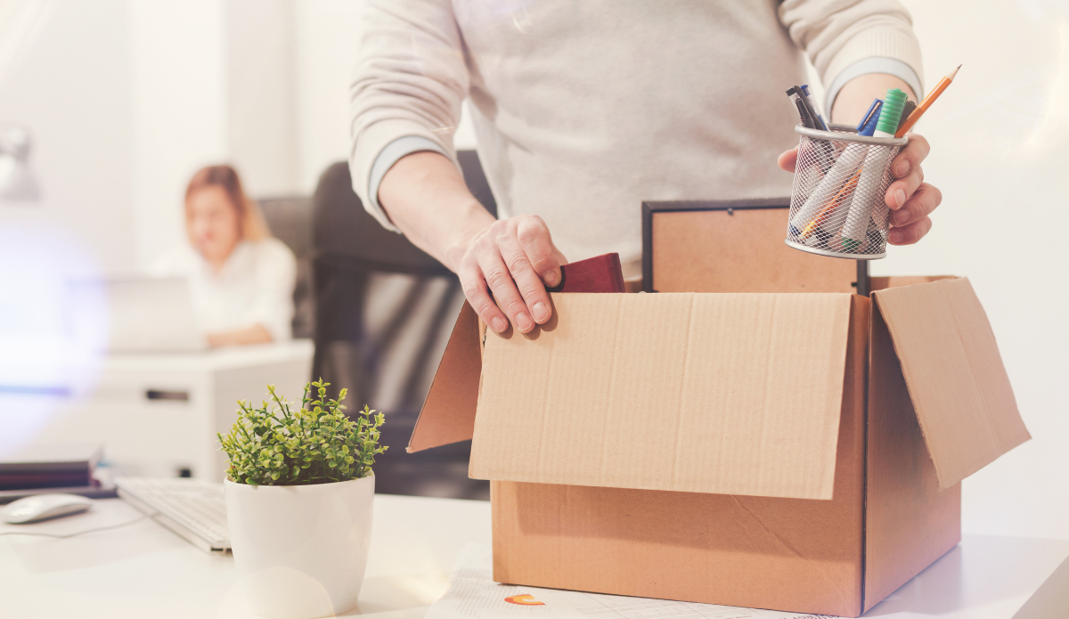 Un hombre está empacando sus pertenencias en una caja de cartón.