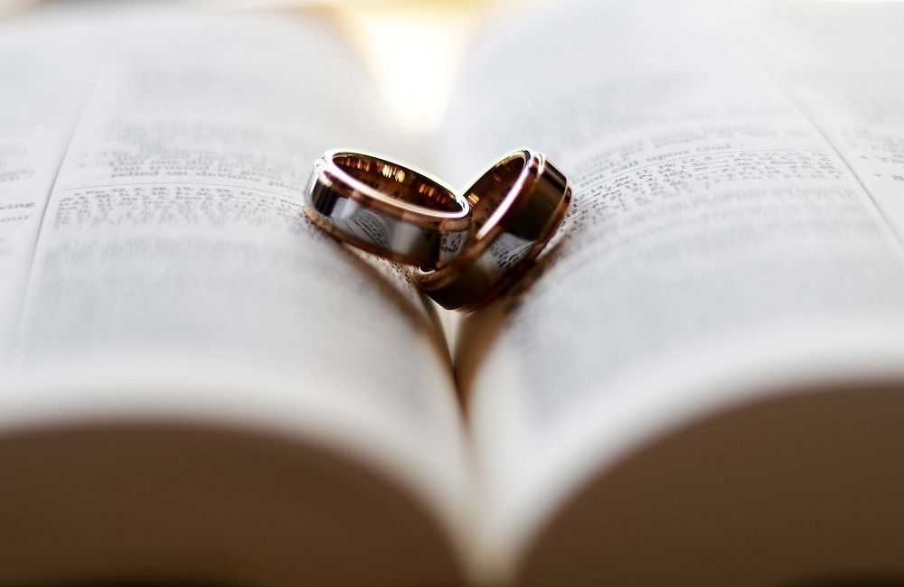 Dos anillos de boda están encima de una Biblia abierta.