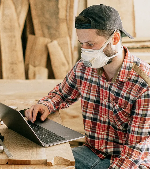 Un hombre que lleva una máscara está usando una computadora portátil.