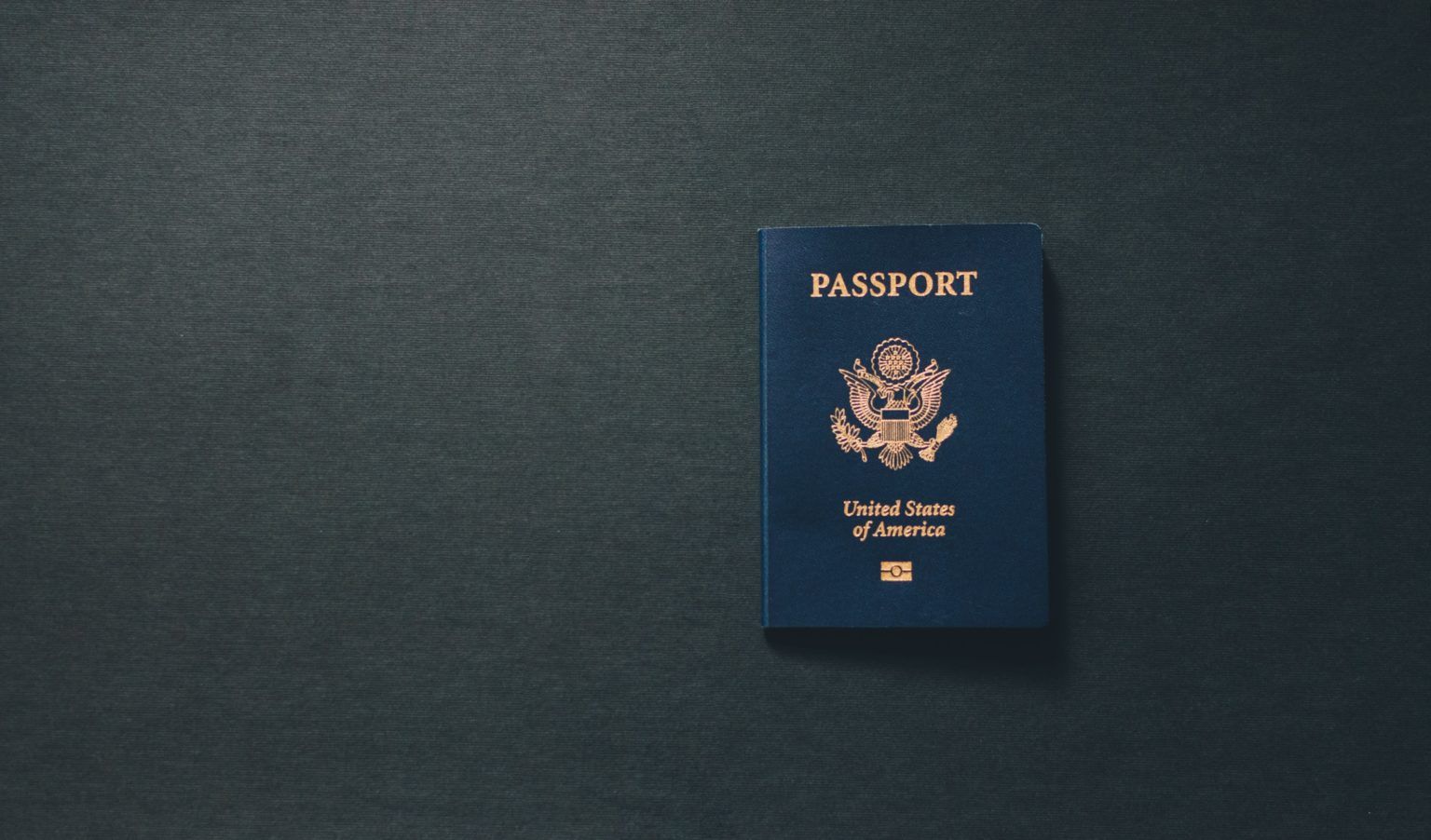 Un pasaporte azul está sobre una superficie negra.