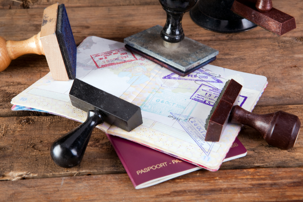 Una mesa de madera cubierta de pasaportes, sellos y un globo terráqueo.