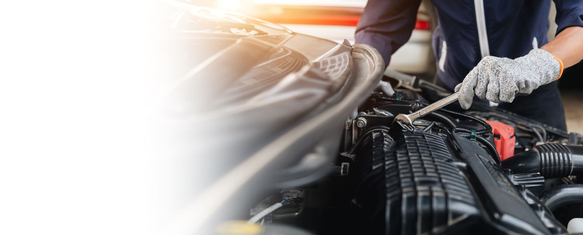 Un mécanicien ganté utilise une clé pour effectuer l'entretien d'un moteur de voiture.
