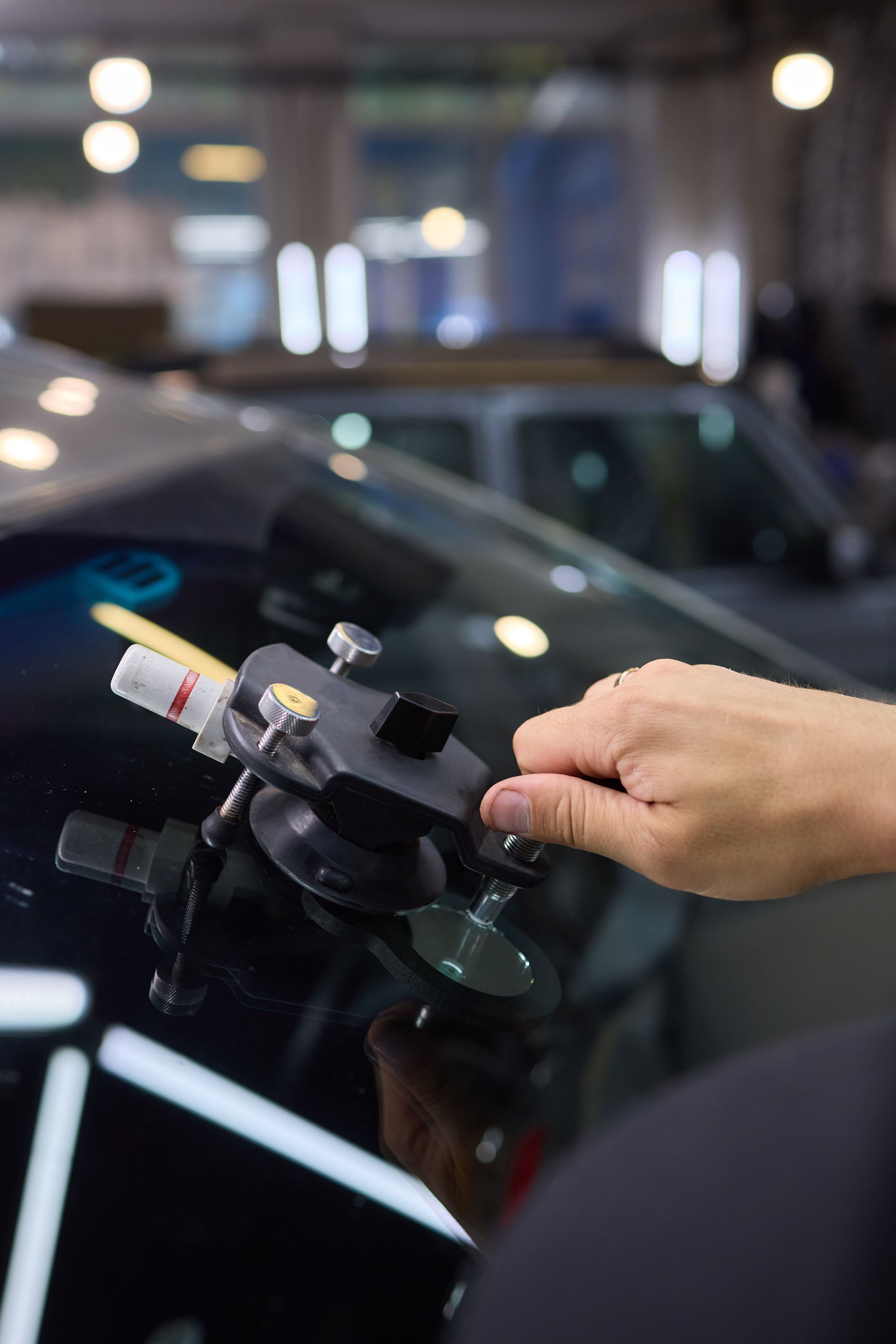 Un technicien utilise un outil professionnel à ventouses pour réparer une fissure sur un pare-brise de voiture.