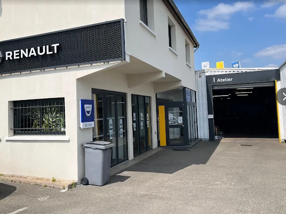 Un bâtiment de concession Renault avec une façade claire, une entrée vitrée et un garage.