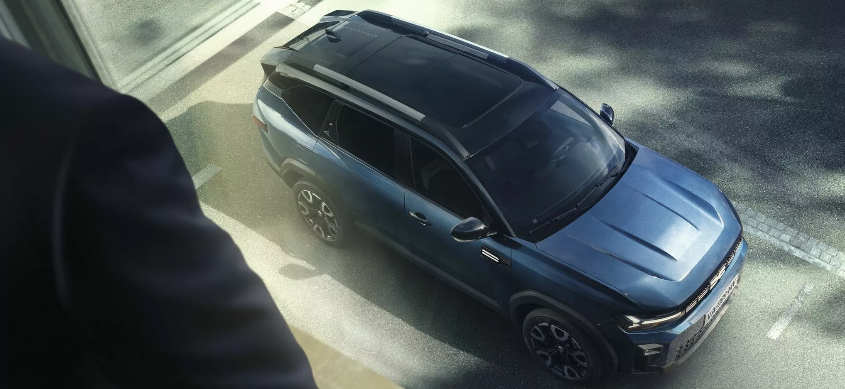 Vue en plongée d'un SUV bleu foncé stationné dans une rue de la ville, à côté d'un trottoir.