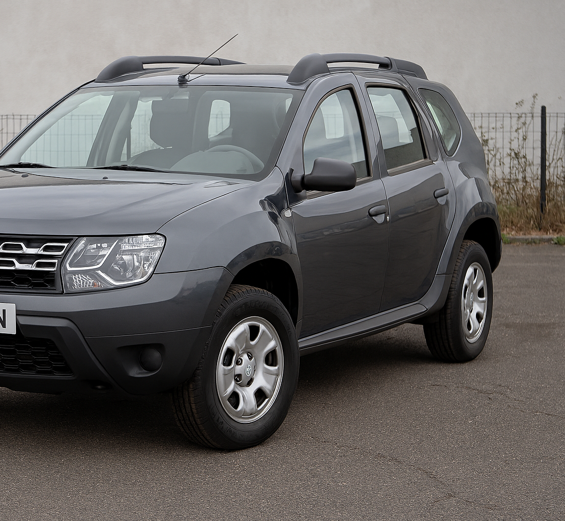Un SUV Dacia Duster gris foncé garé sur le goudron.