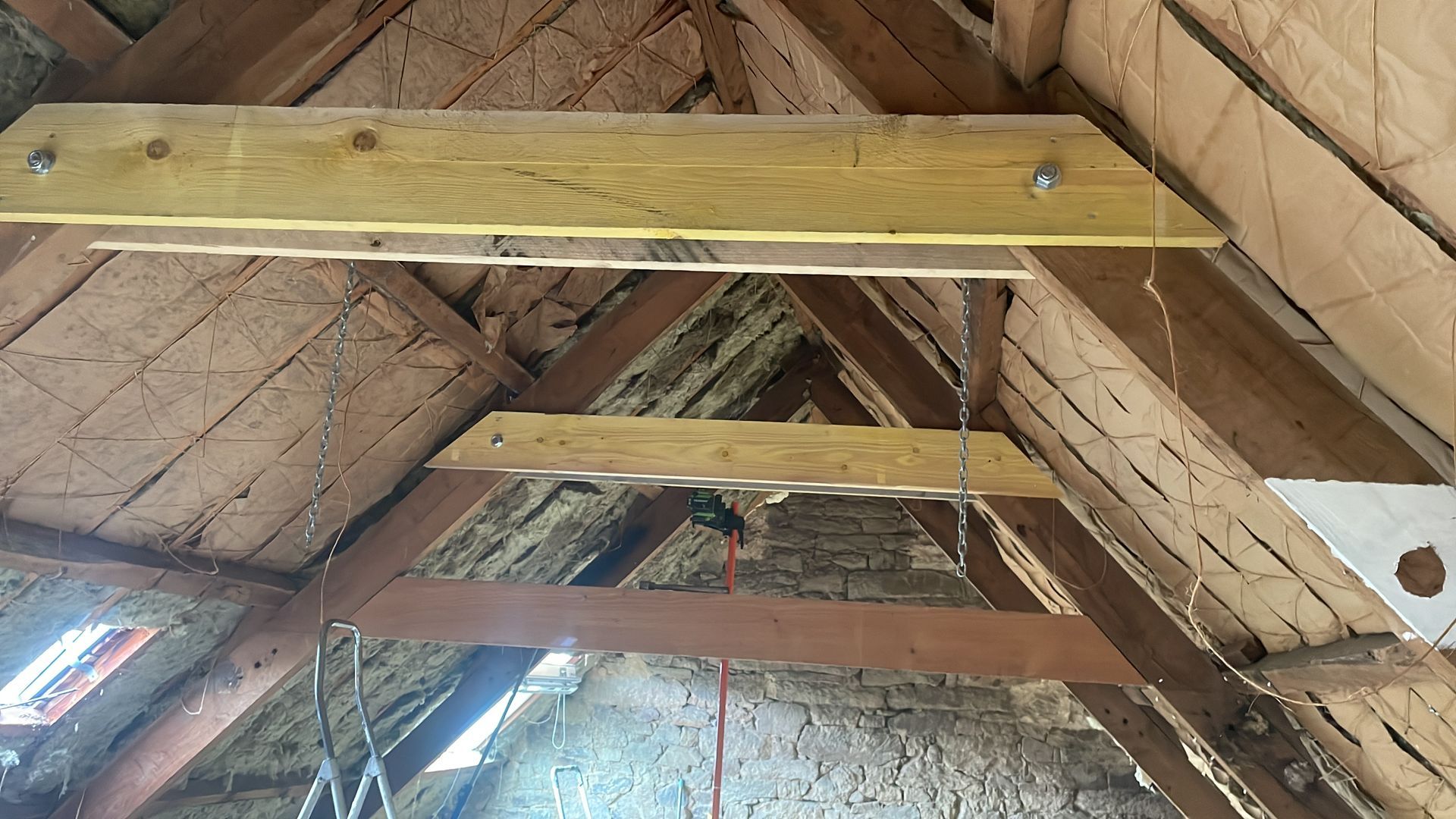 Poutres en bois dans un grenier, l'isolation et la structure porteuse étant visibles.
