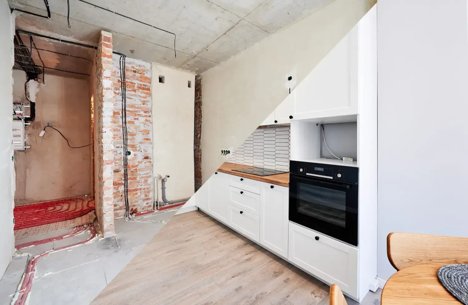 Cocina reformada con armarios blancos, horno negro, pared de ladrillo visto y secciones de techo sin terminar.