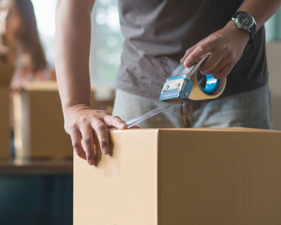 Homme fermant un carton avec du scotch