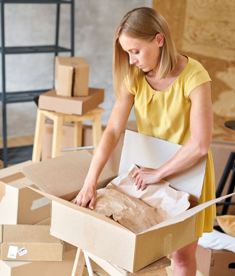 Femme blonde emballant des affaires dans un carton