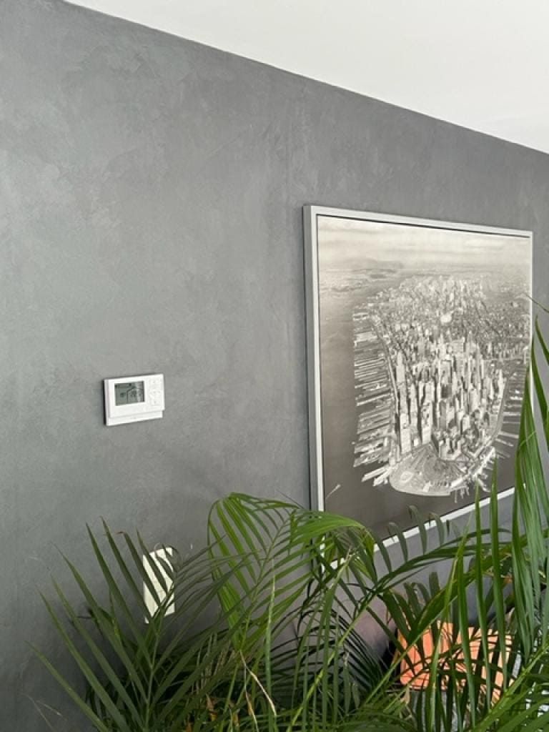 Module de contrôle thermique fixé à un mur gris à côté d'un tableau d'art contemporain