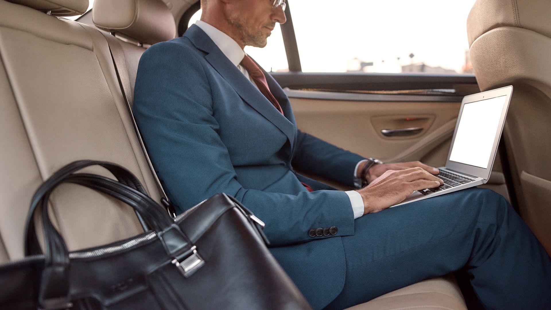 Un homme en costume assis dans une voiture.