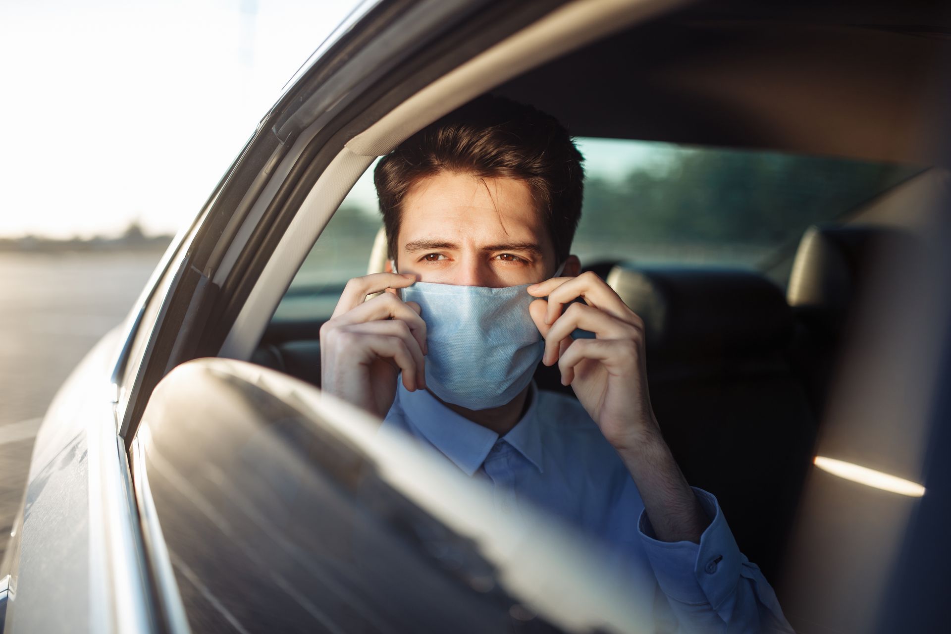 Un homme avec un masque médical dans une voiture.