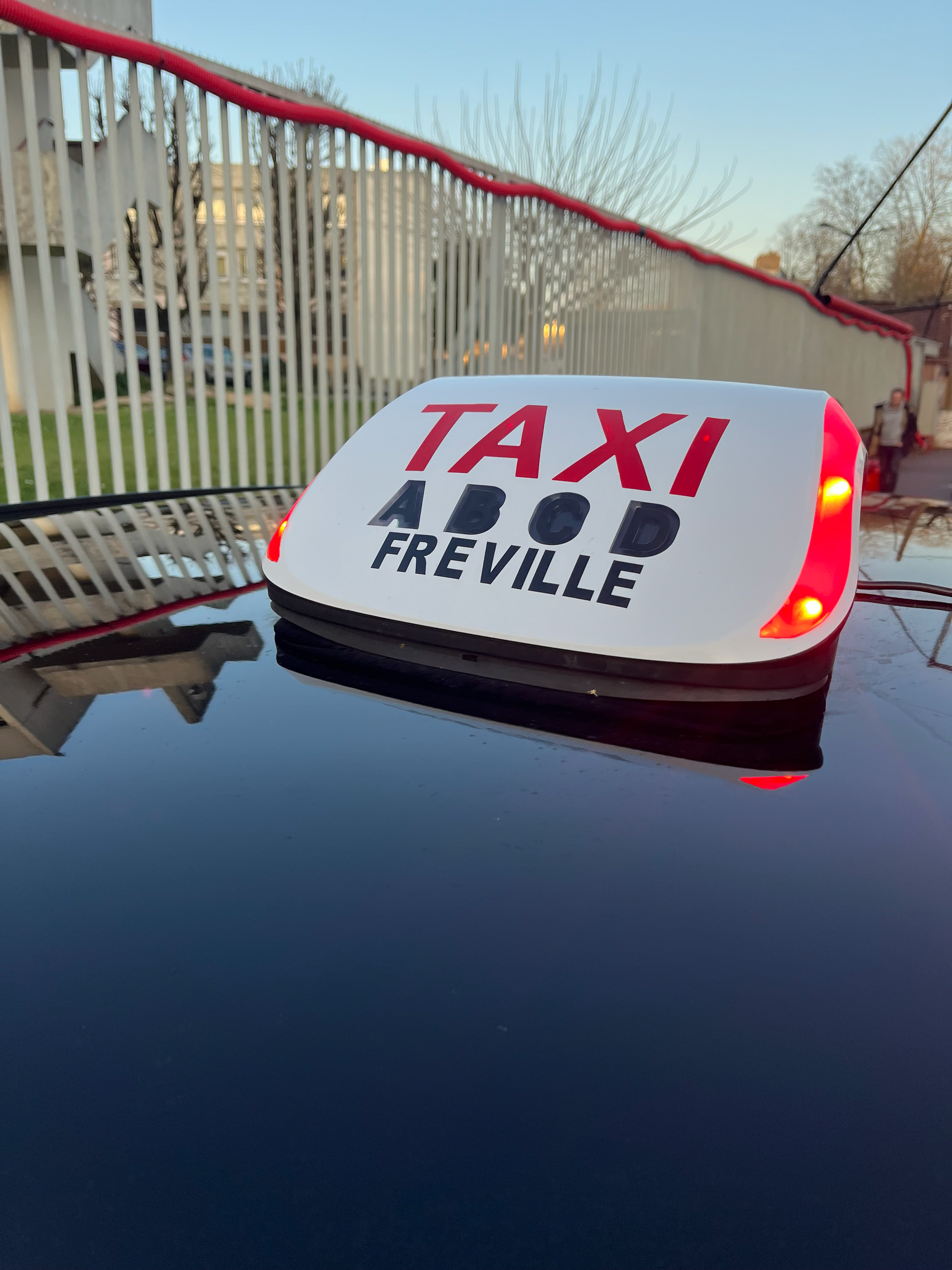 Un lumineux de taxi posé sur une voiture.