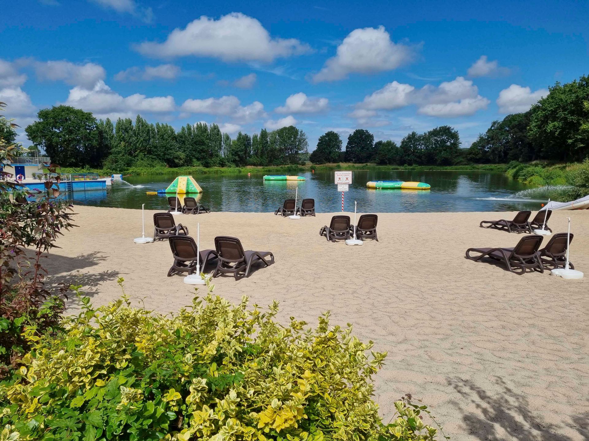 Ein Strand mit Stühlen und Sonnenschirmen neben einem See