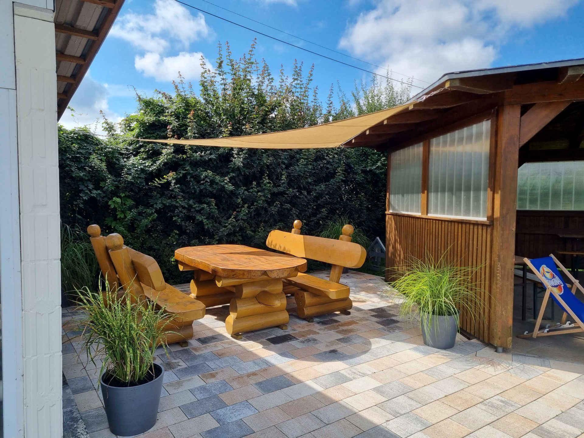 Eine Terrasse mit Tisch und Stühlen unter einem Vordach