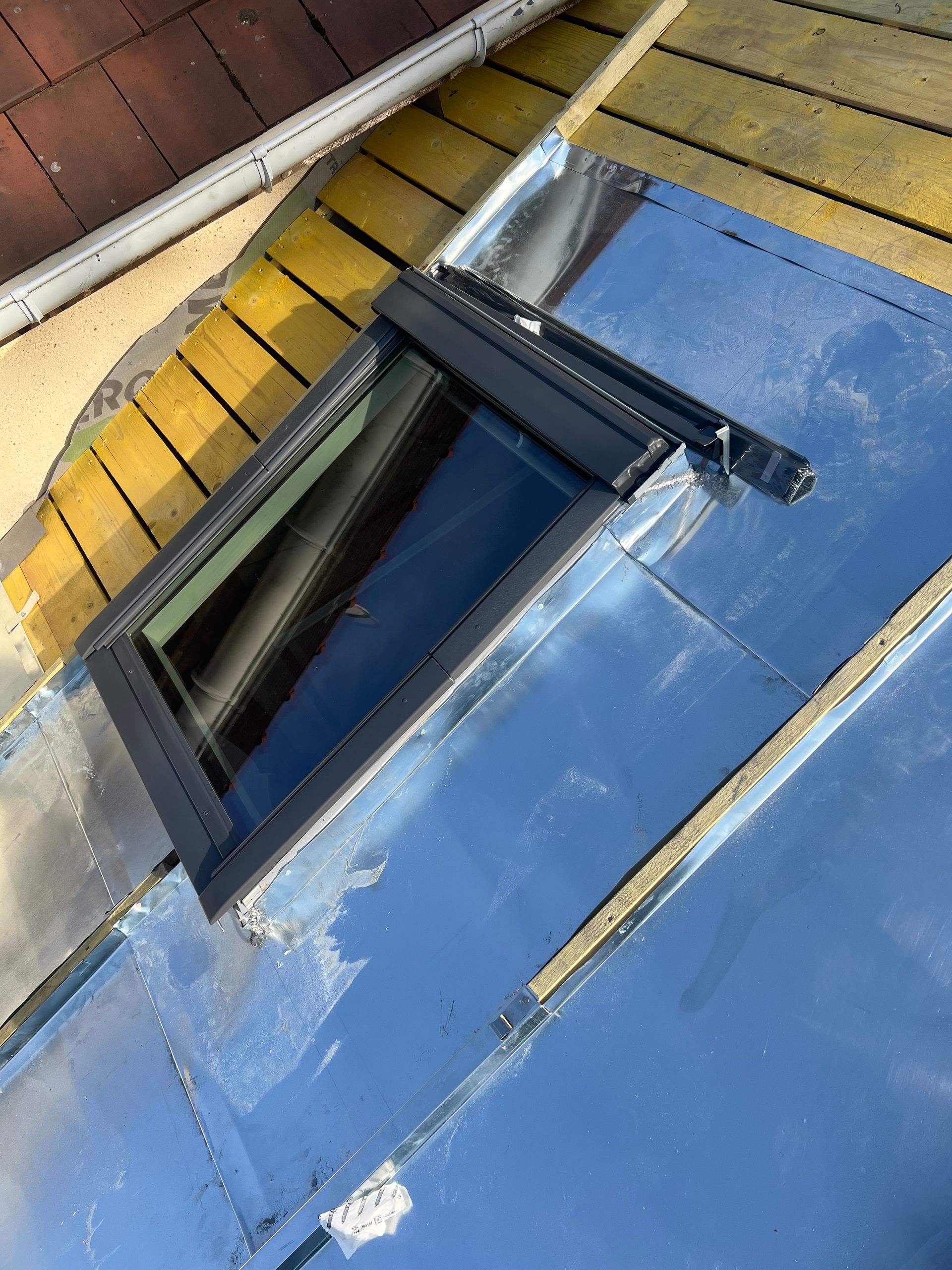 Une fenêtre de toit avec une gouttière en arrière-plan