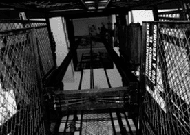 Una fotografía en blanco y negro de un ascensor con una valla de alambre.