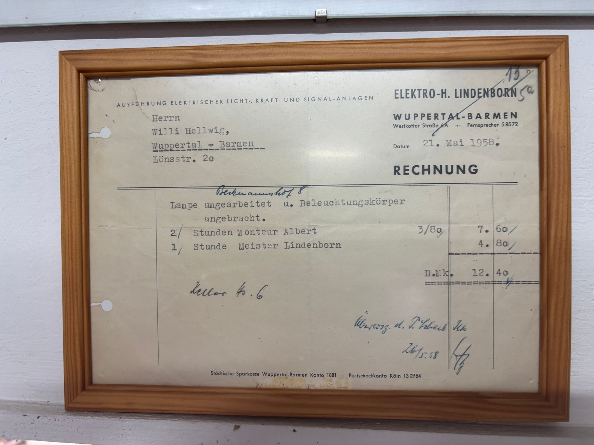 Gerahmte, alte Rechnung mit handschriftlichen Notizen und deutschem Text an einer hellen Wand.