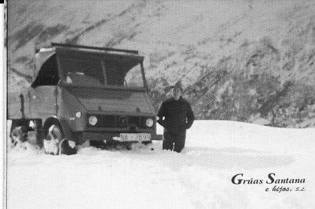 Una fotografía en blanco y negro de un hombre parado junto a un camión en la nieve.