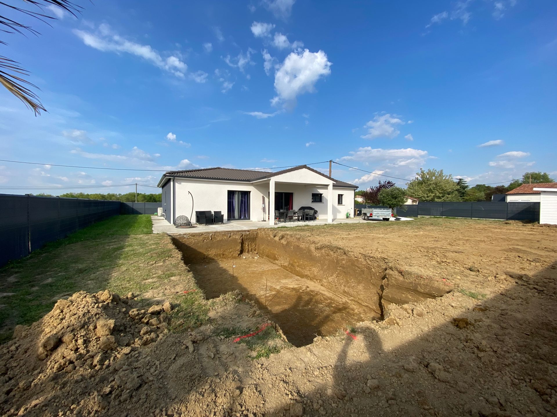 Une maison vue de loin et un rectangle creusé devant cette maison