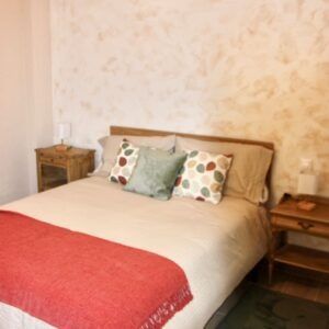 Dormitorio con cama, mesitas de noche y paredes texturizadas color canela.