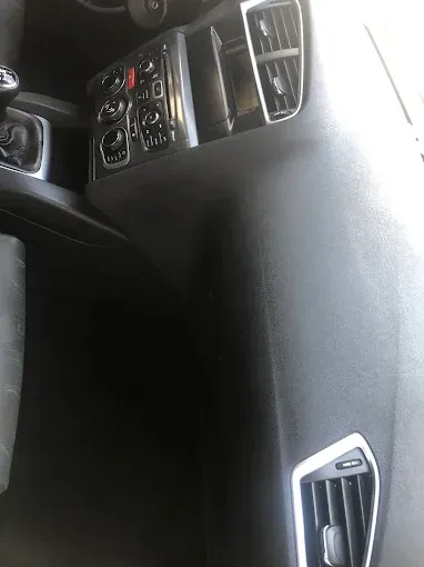 Consola central del salpicadero del coche y salida de aire del lado del pasajero, con controles de climatización