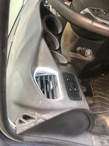 Primer plano de la parte inferior del salpicadero y el espacio para los pies de un coche, con la rejilla de ventilación