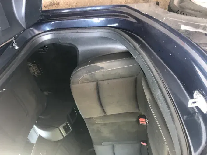 Interior del maletero de un coche con el asiento trasero plegado y tapicería oscura, visto desde la escotilla abierta.