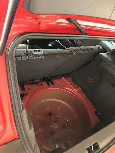 Maletero abierto con el asiento trasero plegado, dejando al descubierto un compartimento rojo