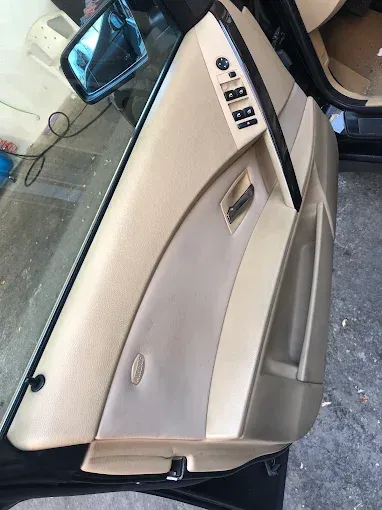Puerta del coche abierta con panel interior beige y botones de control, vista desde fuera en ángulo.