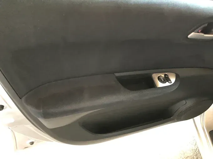 Panel interior de puerta de coche negro con manija plateada y bolsillo de almacenamiento.