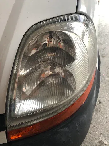 Primer plano del faro delantero y la luz intermitente ámbar de un coche blanco.