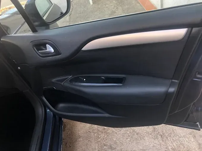 Interior de la puerta trasera del coche abierta, con detalles en negro y tirador plateado, que deja ver el panel de la puerta
