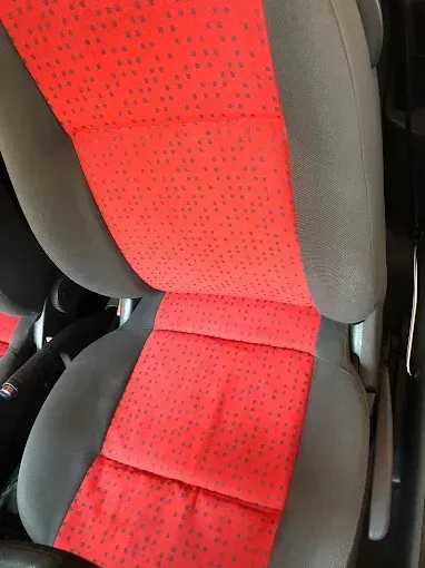 Primer plano de un asiento de coche con estampado rojo y negro y refuerzos laterales grises.