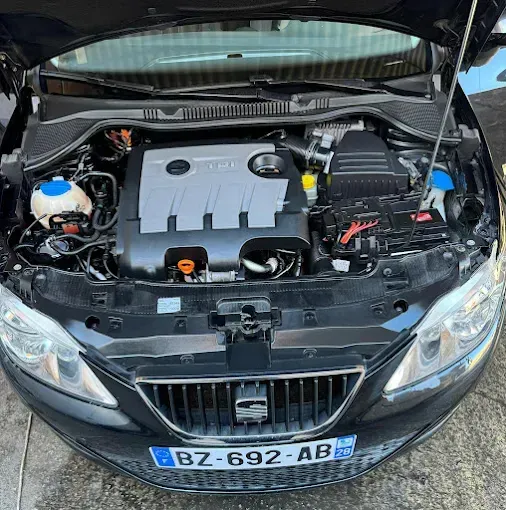Coche negro con el capó abierto, dejando ver el compartimento del motor y la parrilla delantera.