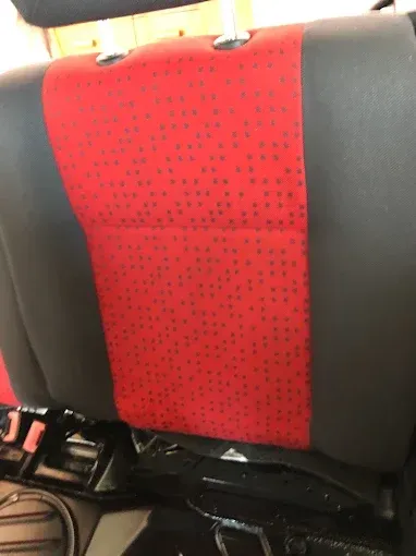 Respaldo de asiento de coche con estampado rojo y negro, con cinturón de seguridad y hebilla visibles en la parte inferior.