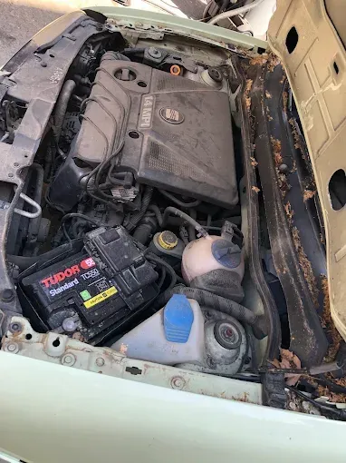 Compartimento del motor del coche con la batería y los depósitos de fluidos, mostrando daños por quemaduras y escombros